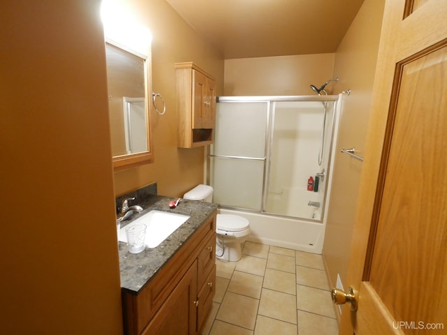 full bathroom with combined bath / shower with glass door, vanity, tile patterned flooring, and toilet