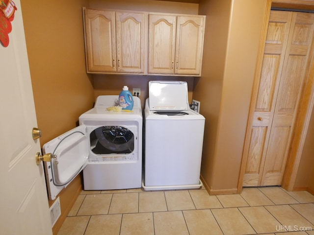 washroom featuring light tile patterned floors, washer and dryer, and cabinets