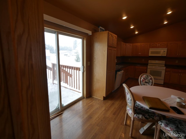 kitchen featuring white appliances, hardwood / wood-style floors, and vaulted ceiling