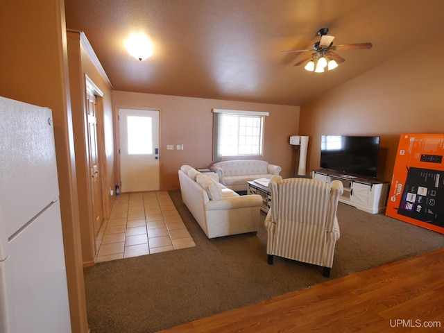 carpeted living room with ceiling fan and vaulted ceiling