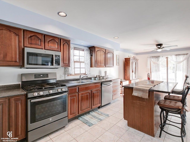 kitchen with ceiling fan, sink, crown molding, appliances with stainless steel finishes, and light tile patterned floors