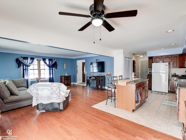 living room featuring ceiling fan, sink, light hardwood / wood-style flooring, and ornamental molding