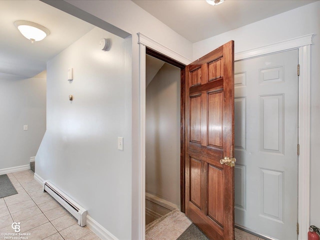 corridor featuring a baseboard heating unit and light tile patterned flooring