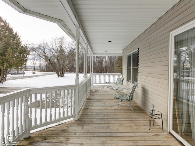 snow covered deck featuring a porch