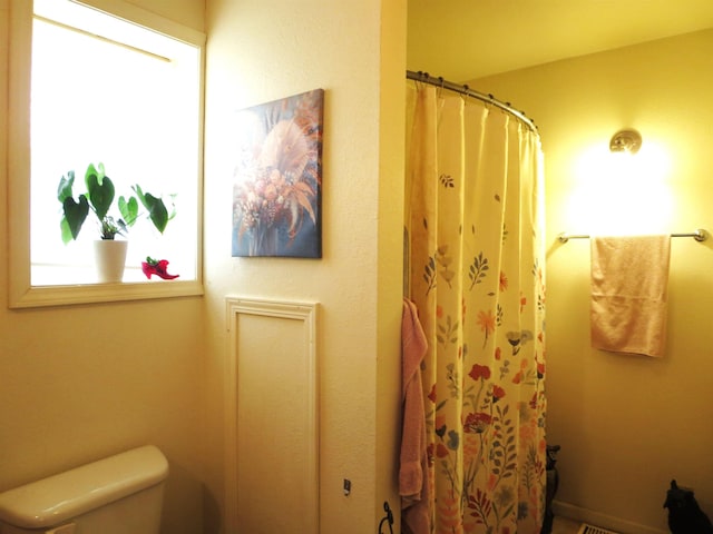 bathroom featuring toilet and curtained shower