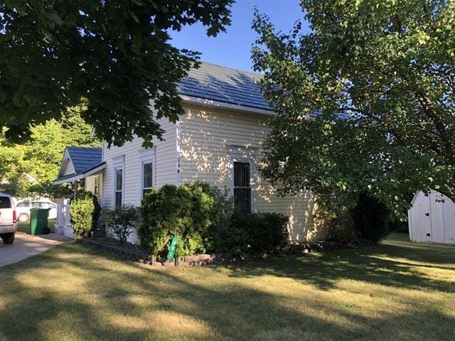 view of side of property featuring a yard and a shed