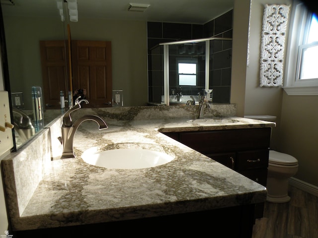 bathroom featuring vanity, toilet, and a shower with shower door