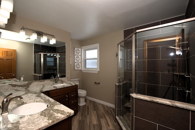 bathroom with a shower with door, wood-type flooring, vanity, and toilet