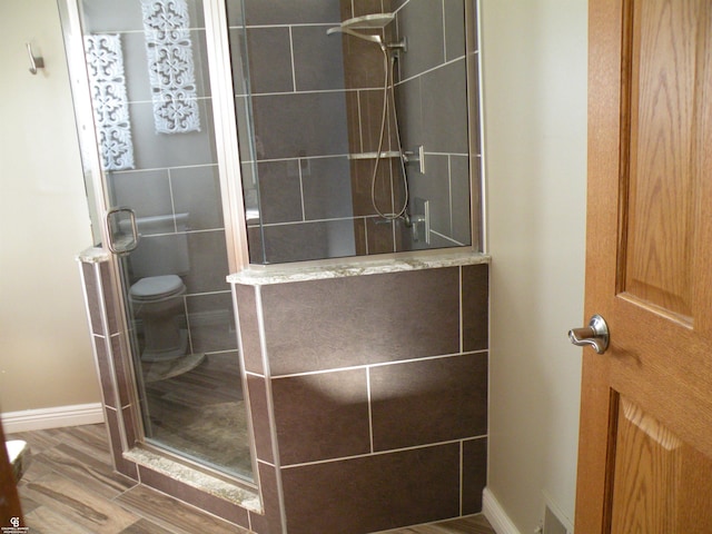 bathroom featuring toilet and a shower with shower door