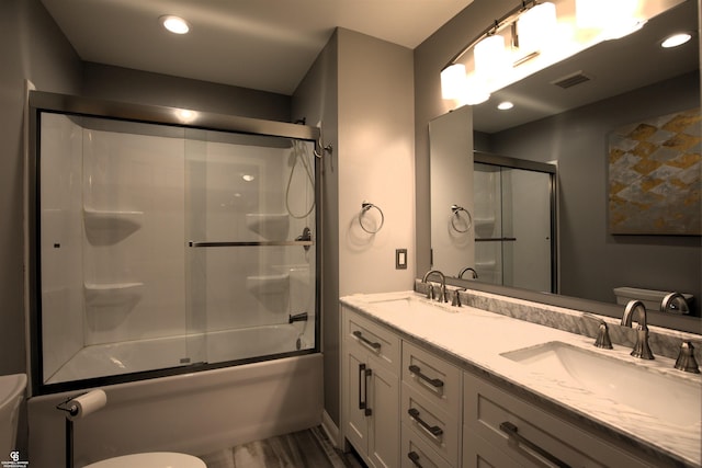 full bathroom featuring vanity, hardwood / wood-style floors, shower / bath combination with glass door, and toilet