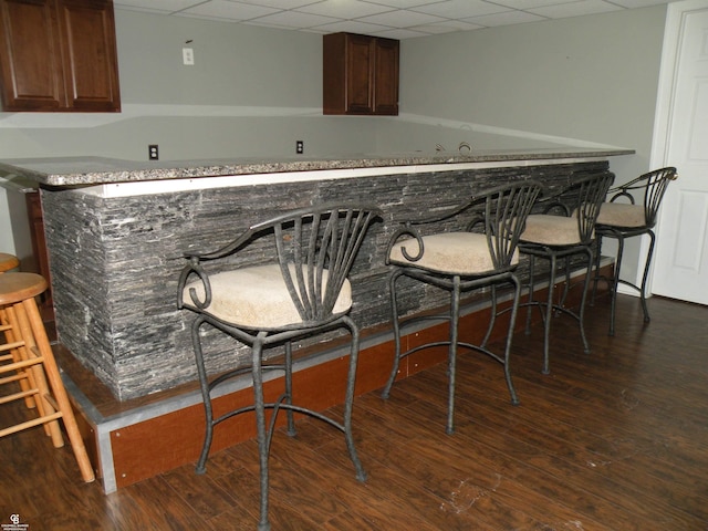 bar featuring a paneled ceiling and dark hardwood / wood-style flooring