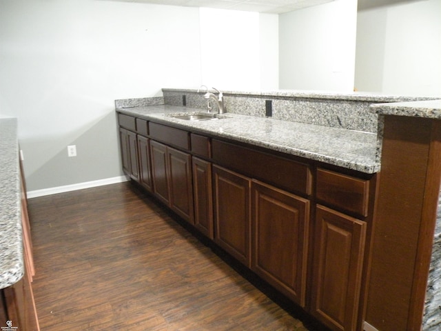 kitchen featuring dark wood-type flooring, light stone countertops, and sink