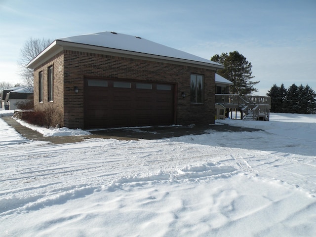 view of snow covered exterior featuring a wooden deck and a garage