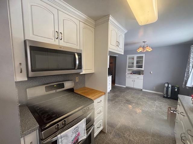 kitchen with tasteful backsplash, appliances with stainless steel finishes, an inviting chandelier, and white cabinetry