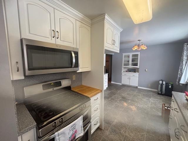 kitchen with appliances with stainless steel finishes, a chandelier, white cabinetry, and tasteful backsplash