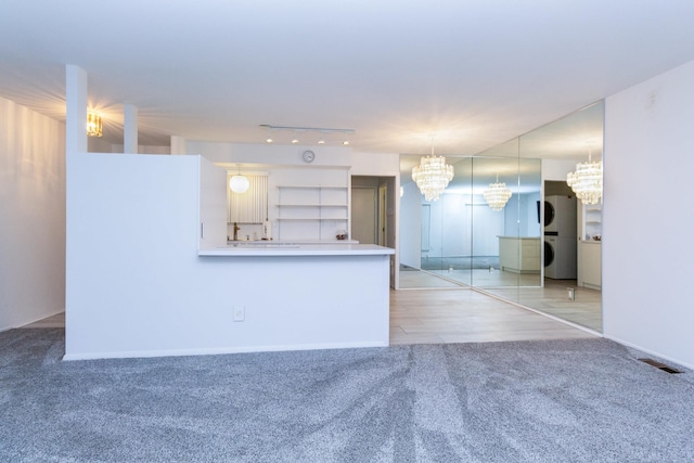 interior space with light colored carpet, hanging light fixtures, kitchen peninsula, and a chandelier