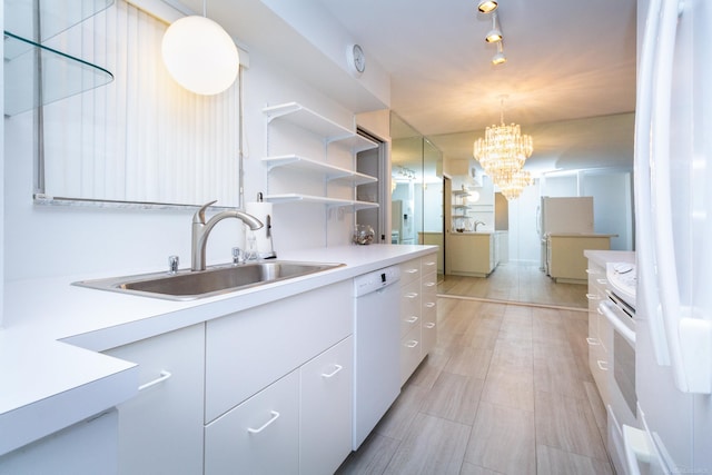 kitchen with decorative light fixtures, sink, white cabinetry, and white appliances