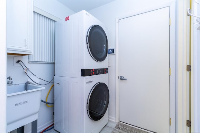 laundry area featuring stacked washer and clothes dryer and sink