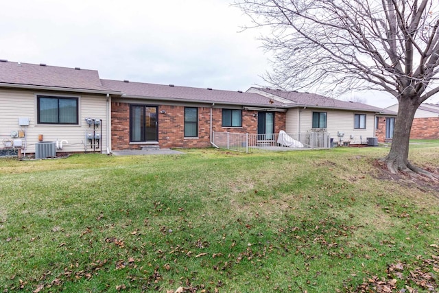 back of house with central AC unit and a lawn