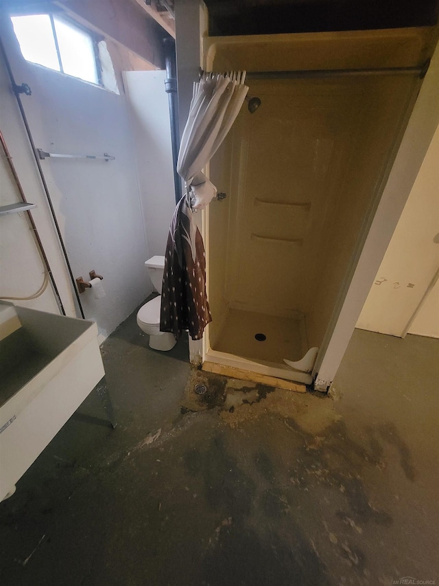 bathroom with curtained shower, concrete floors, and toilet