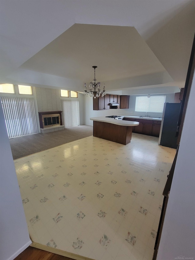 kitchen featuring sink, an inviting chandelier, hanging light fixtures, a kitchen breakfast bar, and a fireplace