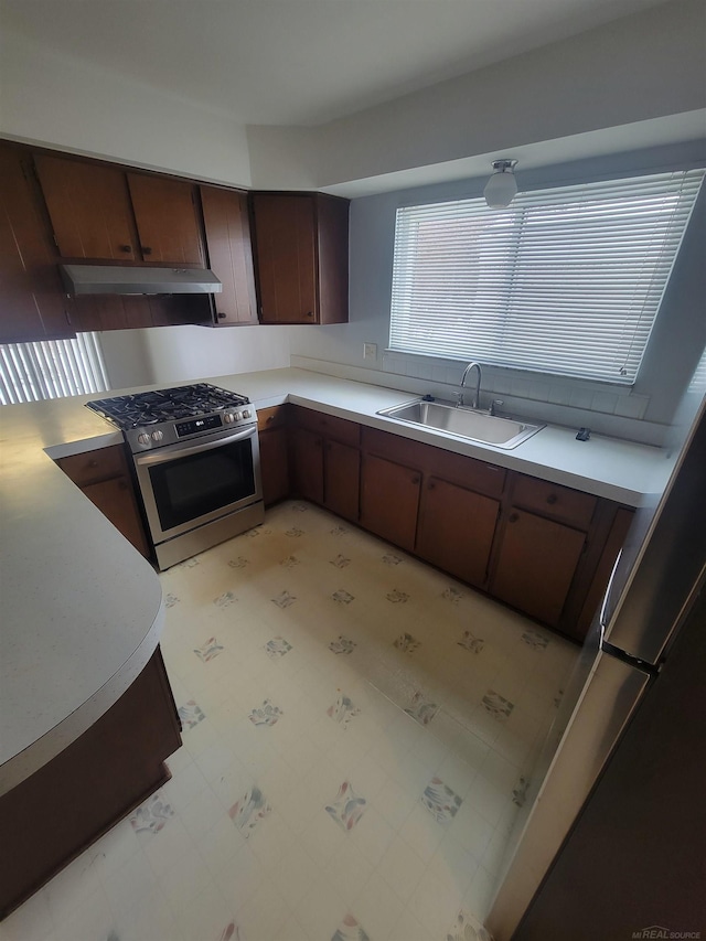 kitchen with dark brown cabinetry, sink, and gas range