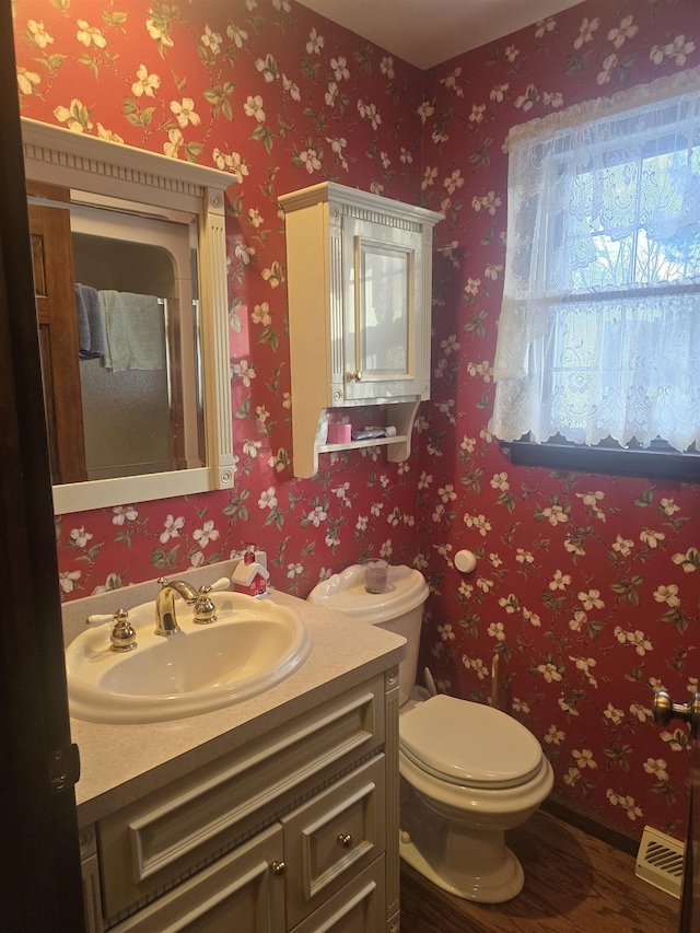 bathroom featuring wood-type flooring, toilet, and vanity