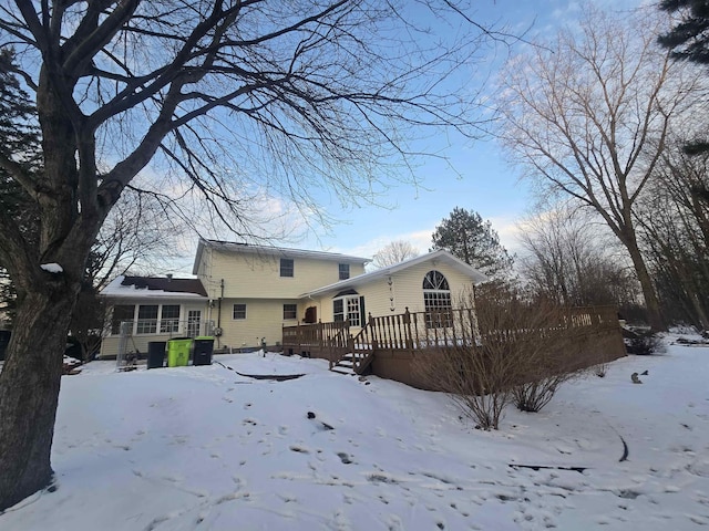 snow covered house featuring a wooden deck