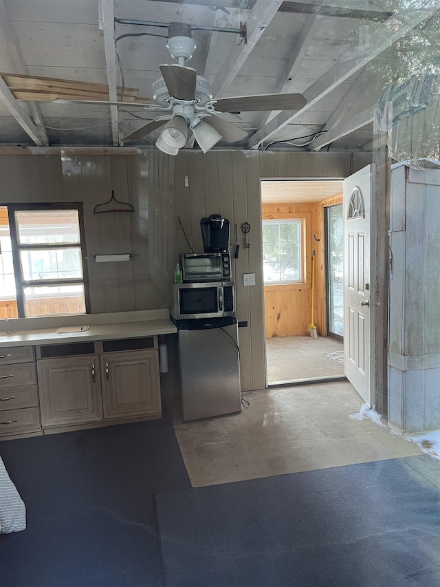 kitchen featuring ceiling fan, wooden walls, and stainless steel appliances