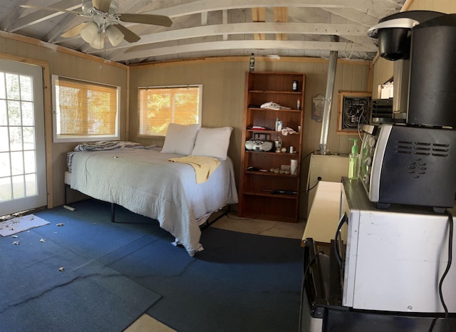 bedroom featuring lofted ceiling and wood walls