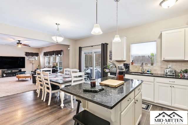 kitchen featuring ceiling fan, a kitchen island, pendant lighting, sink, and white cabinets