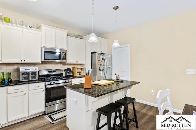 kitchen featuring decorative backsplash, white cabinets, appliances with stainless steel finishes, and a center island