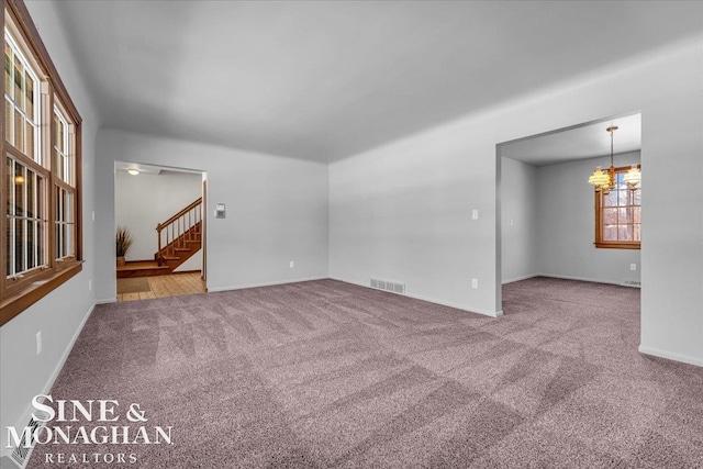 empty room featuring carpet floors and a notable chandelier