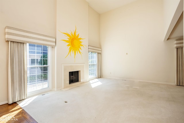 unfurnished living room featuring a towering ceiling, light colored carpet, and a premium fireplace