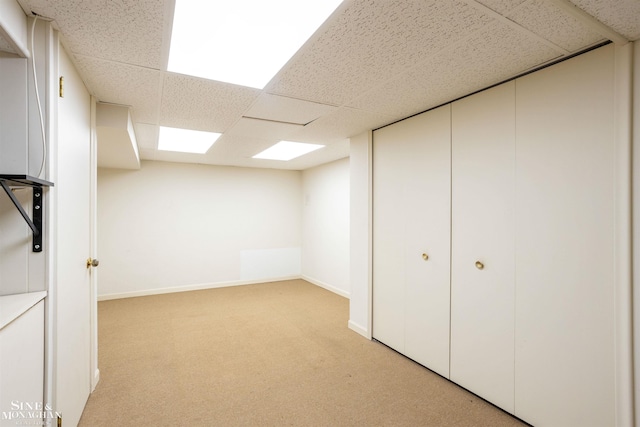 basement featuring light colored carpet and a drop ceiling