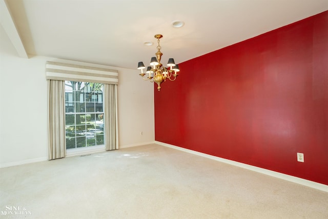 carpeted spare room featuring a chandelier