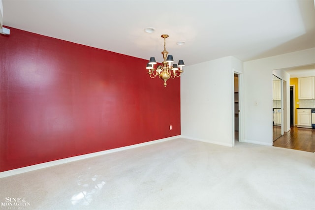 spare room featuring carpet and a chandelier