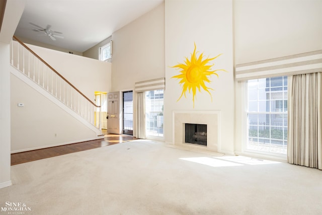 unfurnished living room with carpet floors, a towering ceiling, and ceiling fan