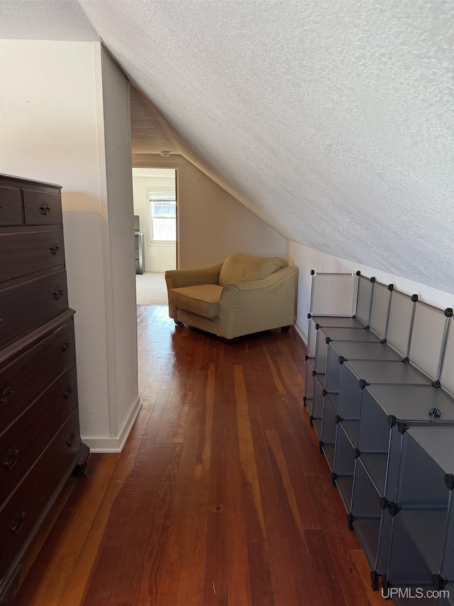 additional living space featuring a textured ceiling, dark hardwood / wood-style flooring, and lofted ceiling