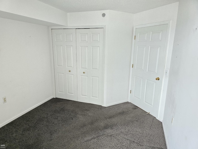 unfurnished bedroom with dark carpet and a closet