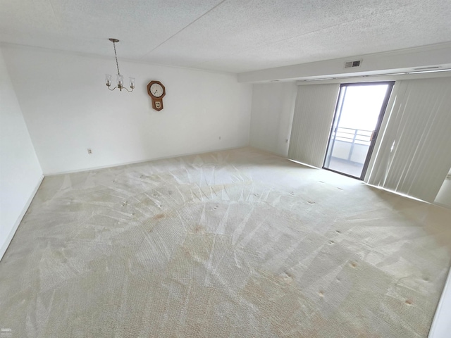 carpeted empty room with a textured ceiling and a notable chandelier