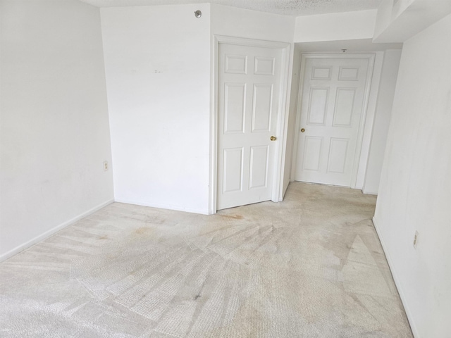 spare room featuring light colored carpet and a textured ceiling