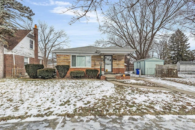 snow covered rear of property with a storage unit