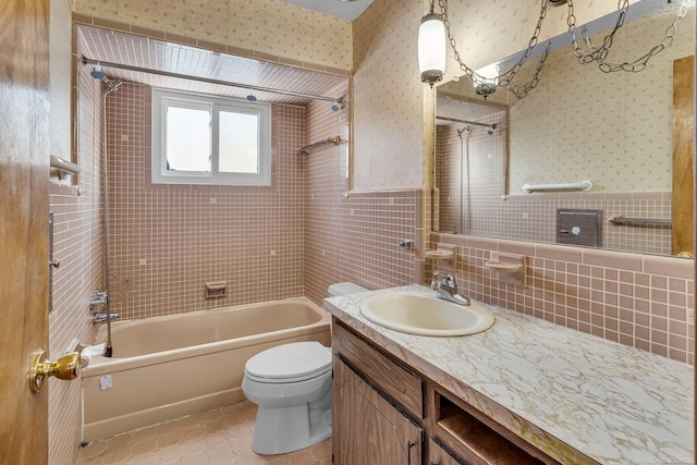 full bathroom with tiled shower / bath combo, tile patterned floors, vanity, tile walls, and toilet