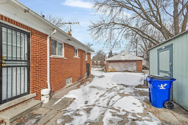 snow covered property featuring a garage and an outdoor structure