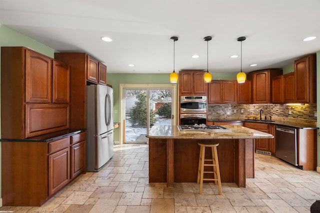 kitchen with appliances with stainless steel finishes, decorative light fixtures, dark stone countertops, a kitchen island, and sink