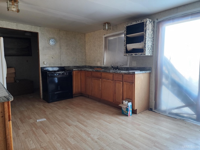 kitchen with light hardwood / wood-style floors, sink, black range with gas cooktop, and white fridge