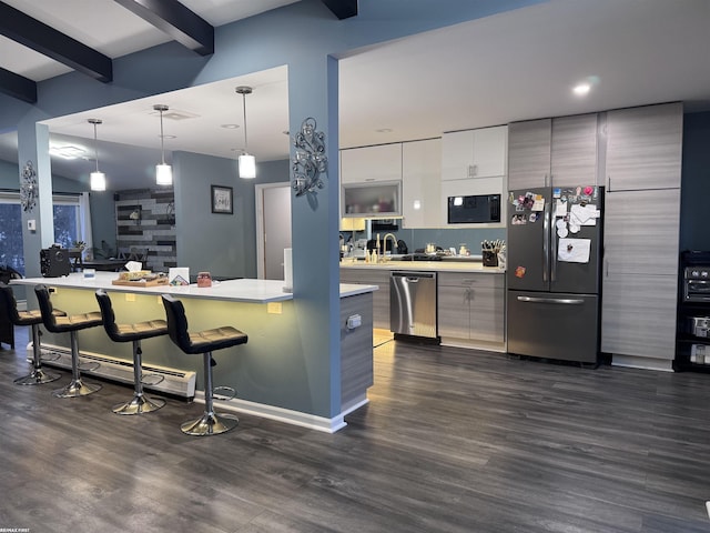 kitchen featuring beam ceiling, light countertops, appliances with stainless steel finishes, a kitchen bar, and modern cabinets