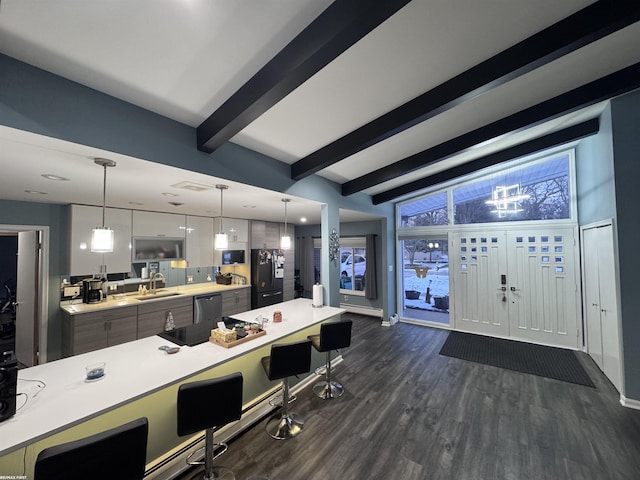 kitchen with a sink, stainless steel dishwasher, dark wood-style floors, a breakfast bar area, and light countertops