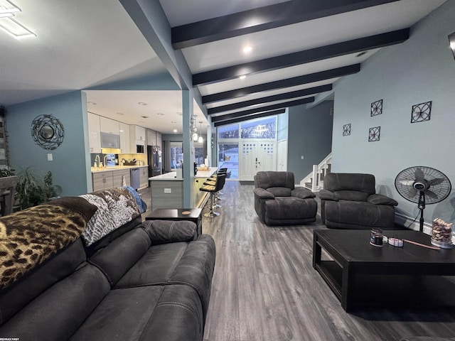 living area with beamed ceiling, wood finished floors, and stairway